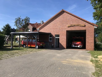 Feuerwehrhaus Tellmer aus Backstein mit zwei roten Einsatzfahrzeugen vor und in der Halle.