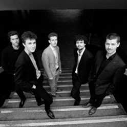 Fünf Musiker des Tobias Haug Quintetts in Schwarz-Weiß auf einer Treppe im Salon de Jazz