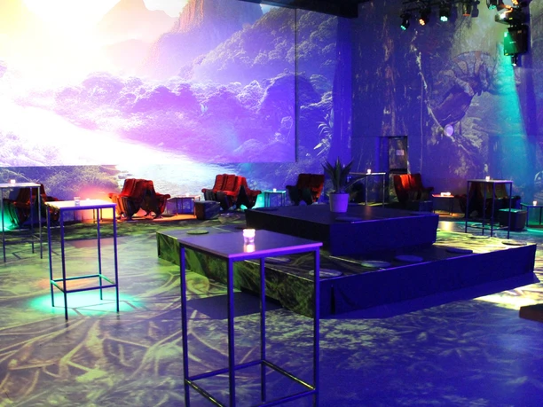 Modern event bar with coloured lights, lounge seating and a large scenic wall projection