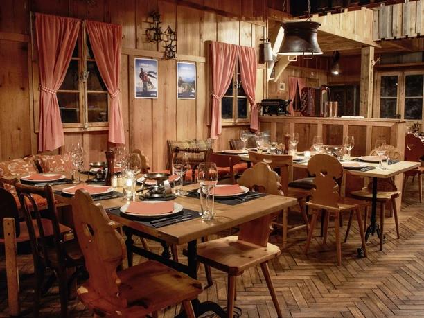 Rustic wooden dining room with set tables, candles and red checked curtains
