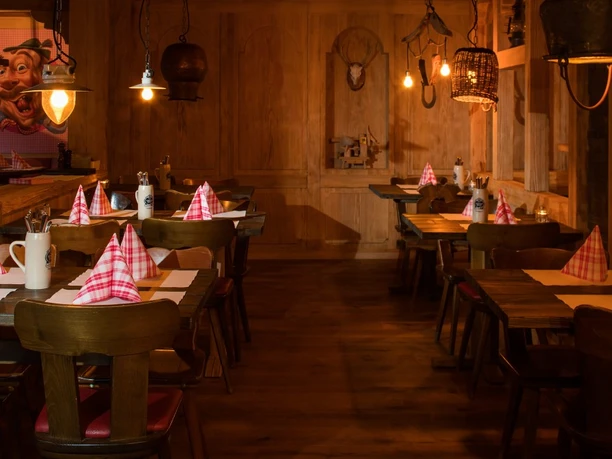 Rustic wooden dining room at Jodlerwirt with checked napkins and warm pendant lights