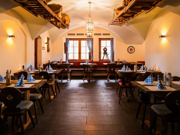 Vaulted Jodlerwirt beer cellar with set wooden tables, warm lights and rustic Swiss décor