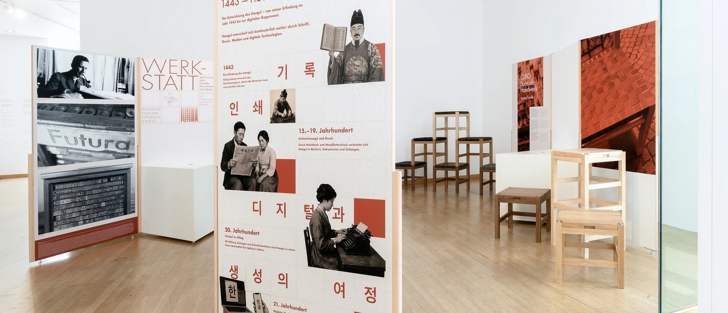 Posters about the Hangul generational series and wooden chairs in the museum.