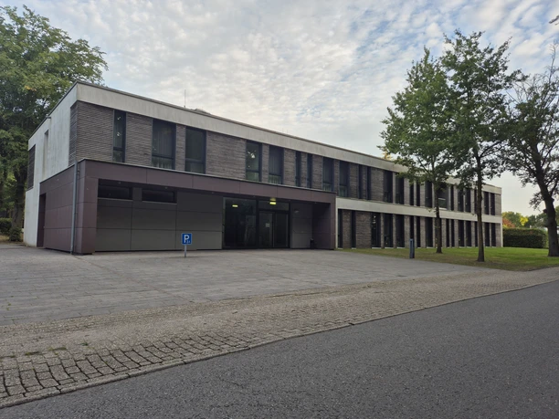 Modernes Gebäude des Evangelischen Bildungshauses Rastede mit Bäumen und Vorplatz.