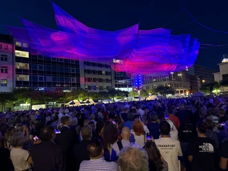 A glowing net installation suspended above a crowd at night in Frankfurt