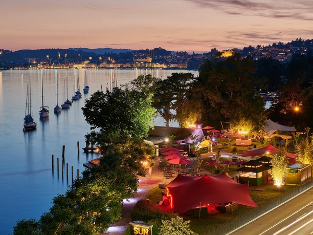 Sunset Bar am Vierwaldstättersee mit roten Zelten, Booten und Luzerner Abendpanorama