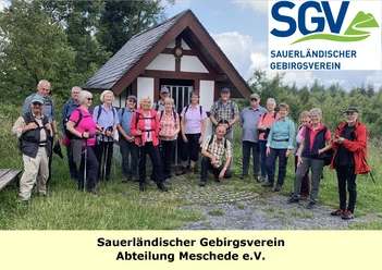 Wandergruppe des SGV Meschede vor kleiner Kapelle mit Vereinslogo