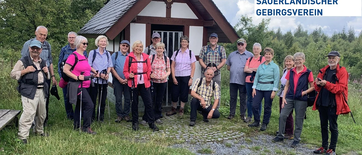 Wandergruppe des SGV Meschede vor kleiner Kapelle mit Vereinslogo