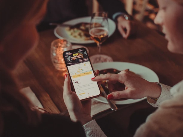 Person bedient Moveat-App am gedeckten Restauranttisch mit Wein und Speisen in Köln