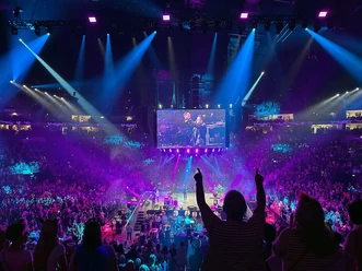 Audience celebrates concert at the LANXESS arena under blue-violet stage lights