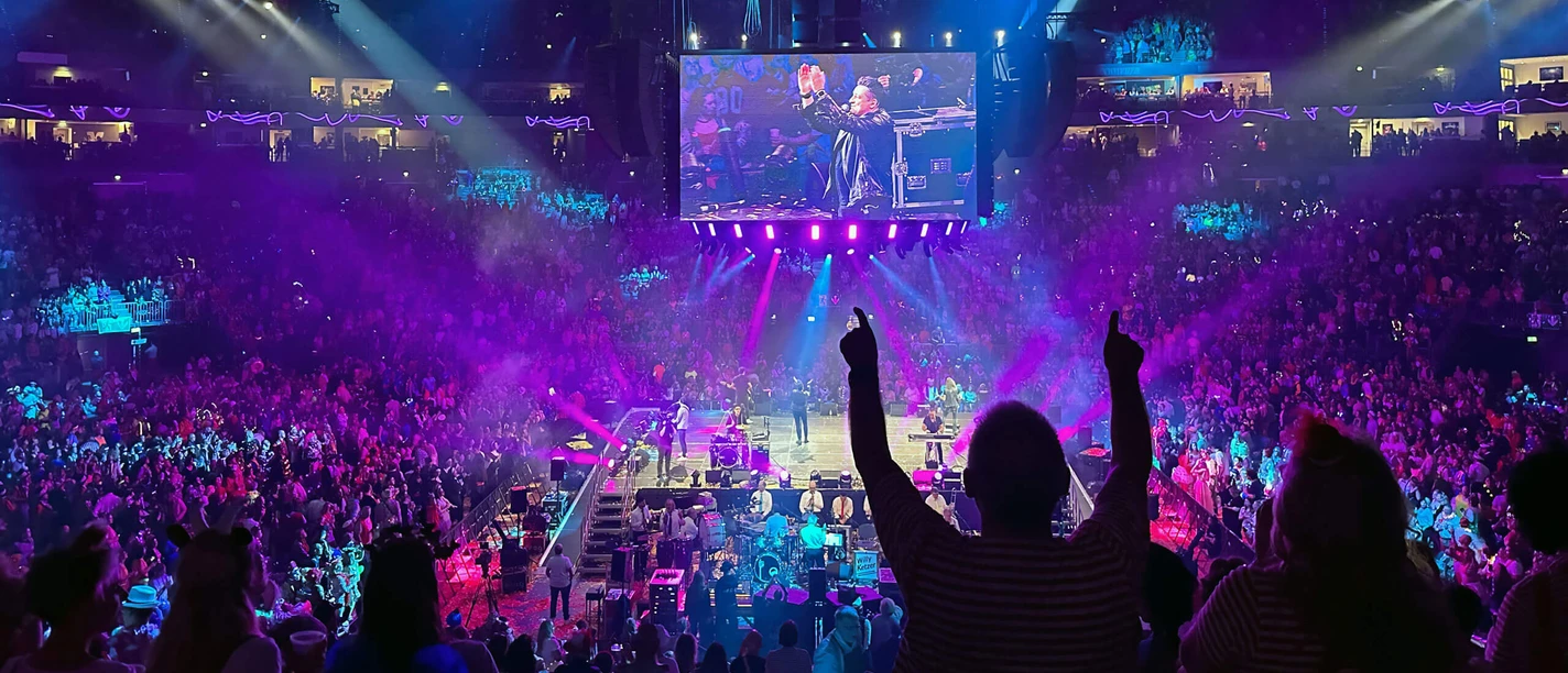 Audience celebrates concert at the LANXESS arena under blue-violet stage lights