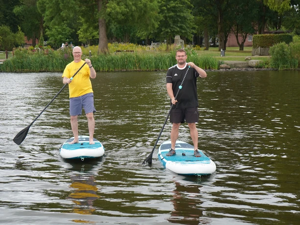 Zwei Männer stehen mit Paddeln auf SUP-Boards auf dem Zwischenahner Meer.