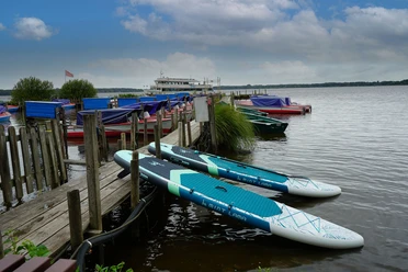 Zwei SUP-Boards am Anleger auf dem Zwischenahner Meer, dahinter Boote und Ausflugsschiff.