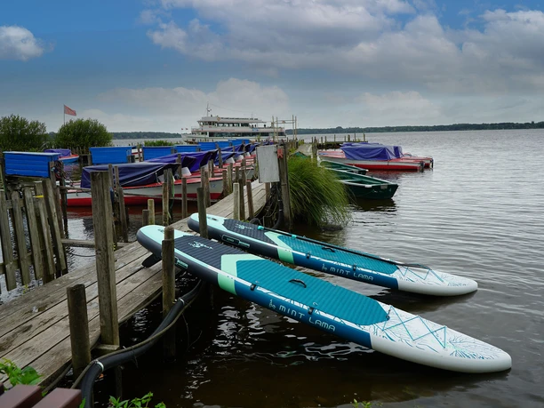 Zwei SUP-Boards am Anleger auf dem Zwischenahner Meer, dahinter Boote und Ausflugsschiff.