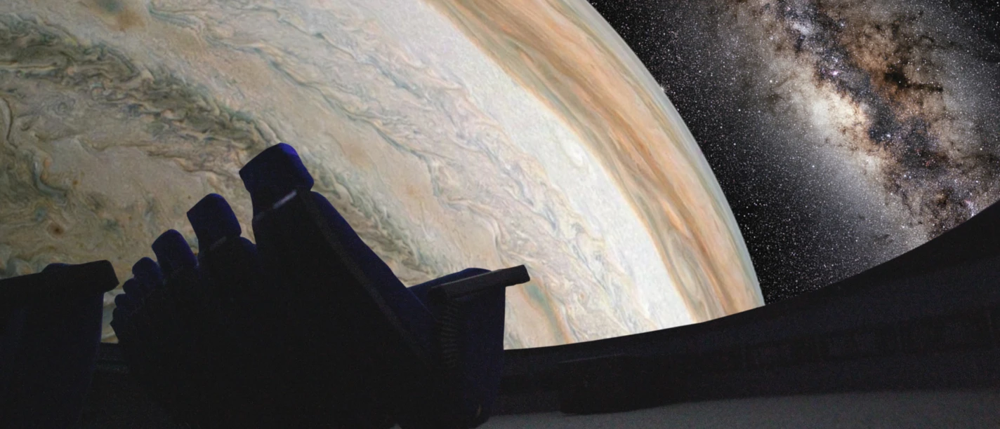 Innenkuppel des Planetariums mit Bestuhlung. Projektion eines Planeten und des Weltalls.