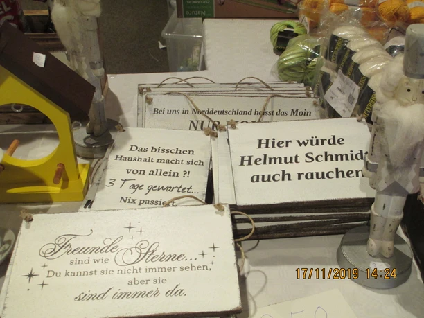 Dekoschilder mit Sprüchen und Holzfiguren auf einem Basartisch in Godensholt.