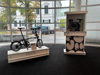 Brompton-Faltrad und gefaltetes Modell in einer Ausstellung im Museum Angewandte Kunst