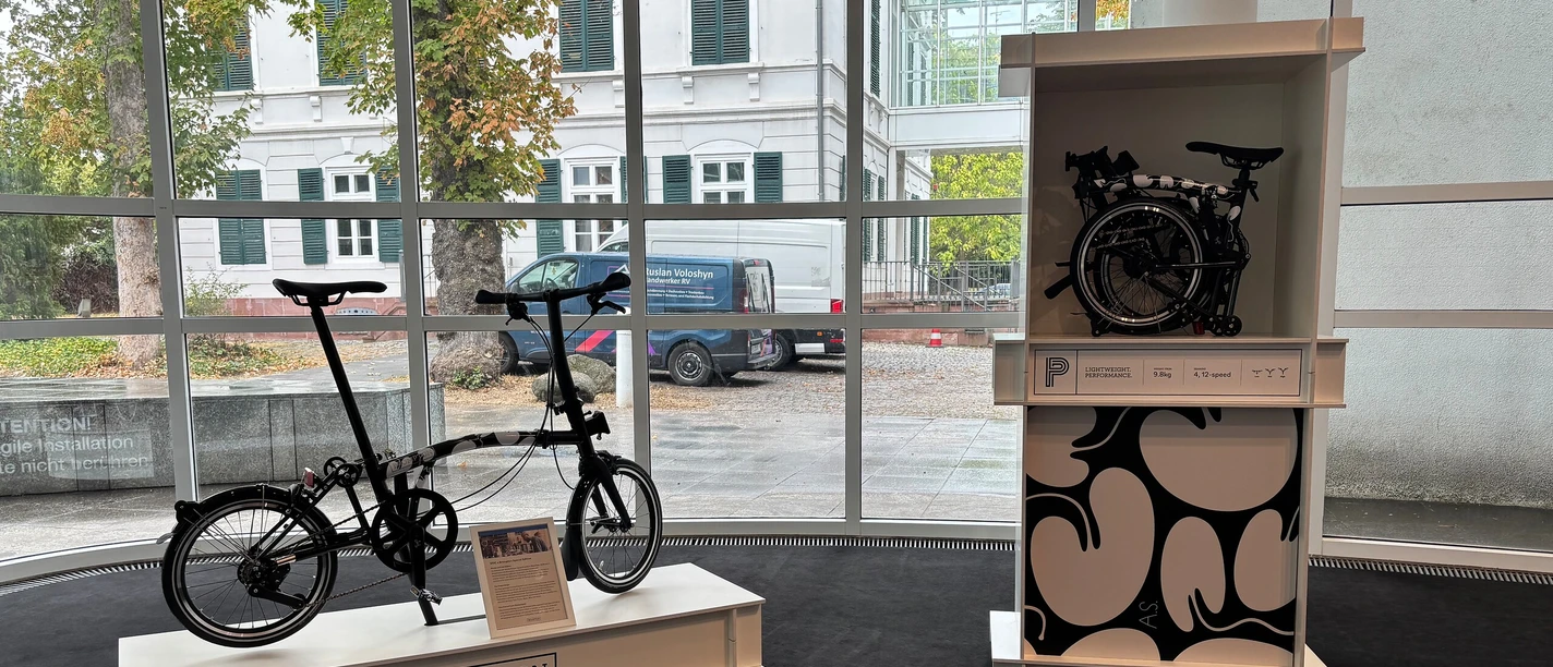 Brompton-Faltrad und gefaltetes Modell in einer Ausstellung im Museum Angewandte Kunst