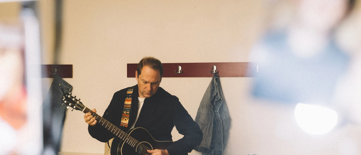 DSCF6895.jpg Thees Uhlmann mit Gitarre in einer Garderobe.