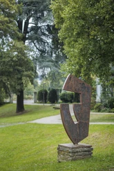 Rostbraune Stahlskulptur Erbgut auf Steinsockel in einer grünen Parkanlage in Burscheid