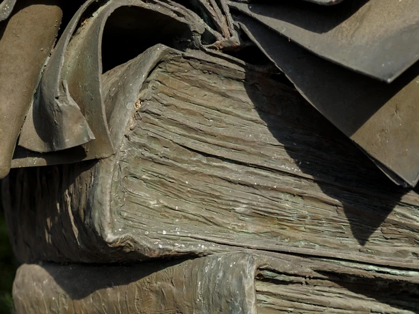 Nahaufnahme der Bronzeskulptur Bücherstapel mit aufgeschlagenen Buchseiten