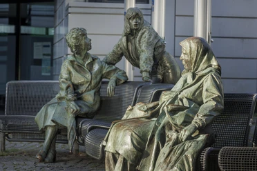 Bronzeskulptur „Begegnung“ mit drei Figuren auf Bänken in Wermelskirchen