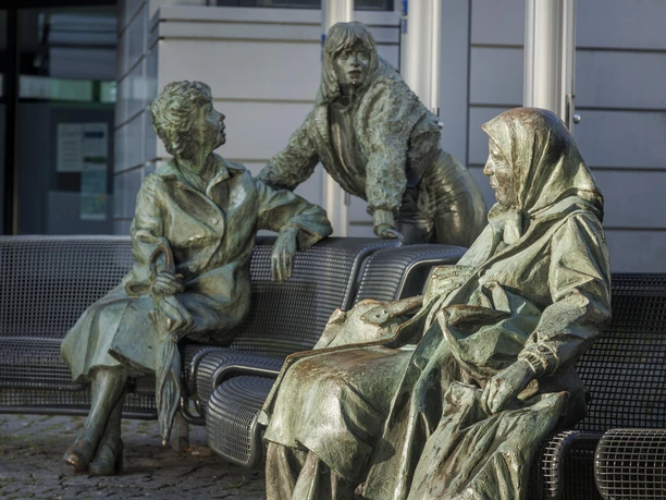 Bronzeskulptur „Begegnung“ mit drei Figuren auf Bänken in Wermelskirchen
