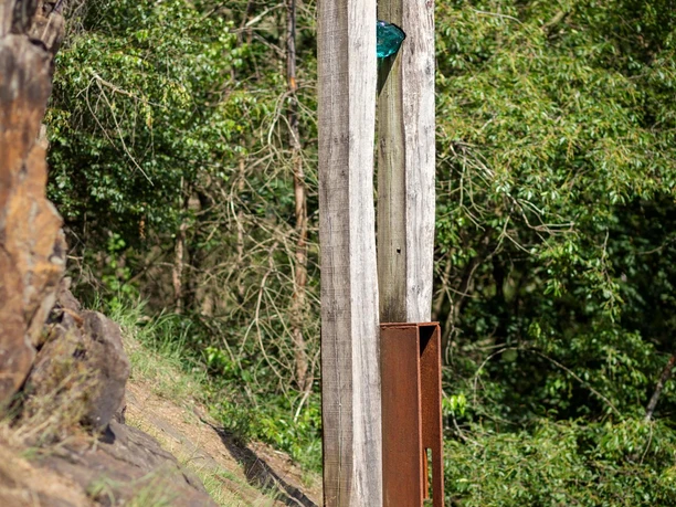 Holz- und Stahlskulptur „Licht“ am bewaldeten Hang