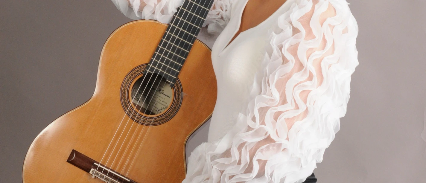 BildEmmaCampas.jpg Emma Campàs lächelt mit klassischer Gitarre vor grauem Hintergrund