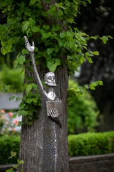 Metallskulptur „Der Prophet“ mit erhobenem Arm vor grünem Laub in Wipperfürth