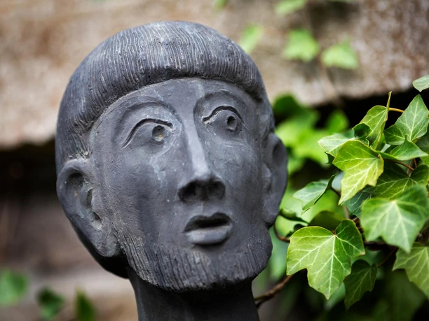 Nahaufnahme des Gesichts der Franziskus-Skulptur von Sepp Hürten mit Efeu