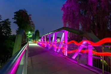 Bogenbrücke in Wipperfürth bei Nacht mit pink-roter Lichtinszenierung über der Wupper