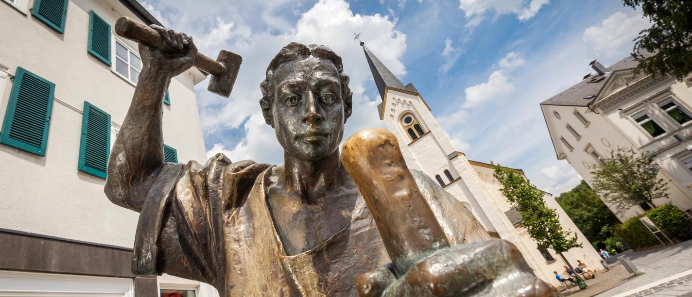 Der Münzschläger Bronzefigur Der Münzschläger mit Hammer vor Kirche in Wipperfürth