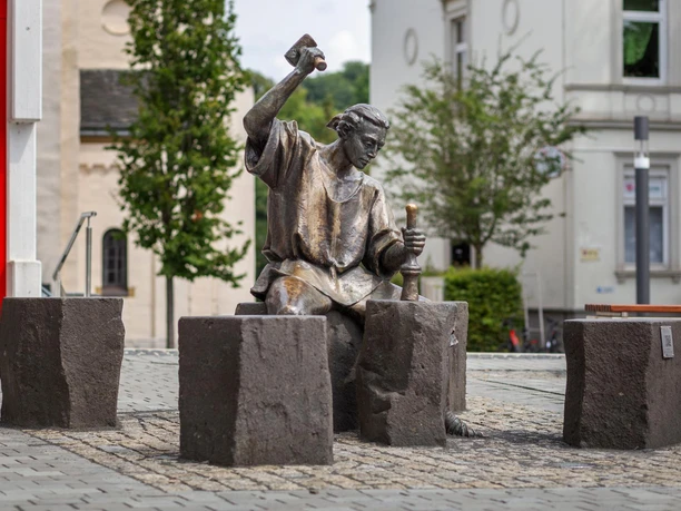 Bronzefigur „Der Münzschläger“ mit erhobenem Hammer auf dem Marktplatz in Wipperfürth