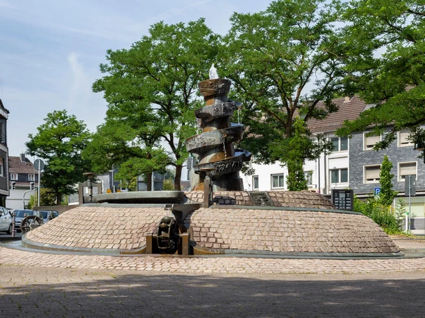 Brunnendenkmal von Bonifatius Stirnberg mit Wasserlauf unter Bäumen in Wipperfürth