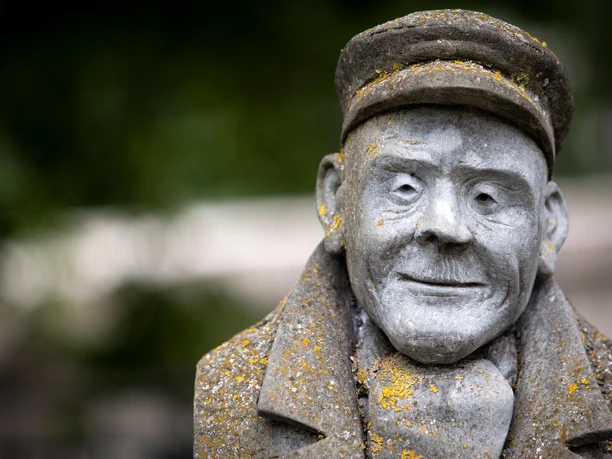 Nahaufnahme der Skulptur Fritz Hamel mit Mütze und verwitterter Oberfläche