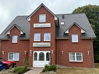 Backsteingebäude des Gästehauses Parrmann mit weißem Eingang und dunklem Ziegeldach.