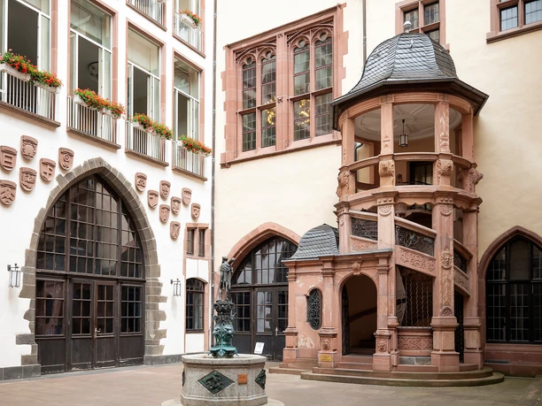 Innenhof des Römers mit Wappen, Rundbogenfenstern und reich verzierter Wendeltreppe