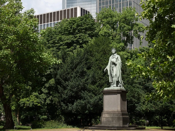 Schiller Monument in the Taunusanlage, surrounded by trees and Frankfurt's high-rises