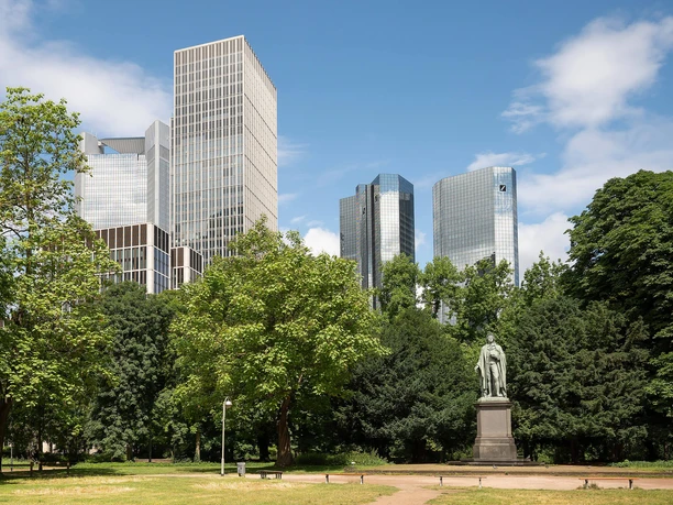 Schiller Monument in the Taunusanlage, set against the backdrop of Frankfurt's skyline and green trees