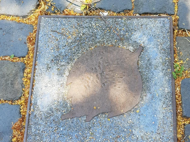 Bodenplatte des Kunstwerks „Blattwerk“ mit Metallblatt zwischen dunklen Pflastersteinen