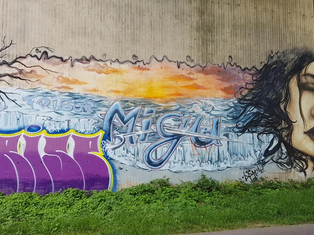Graffiti Graffiti an Betonwand mit Frauenporträt, Eislandschaft und Schriftzügen an der Balkantrasse