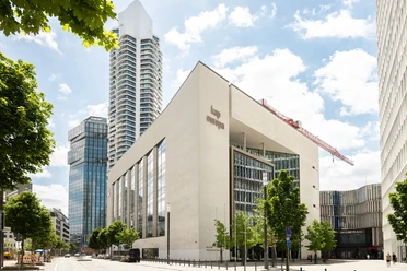 Kap Europa in Frankfurt mit moderner Fassade, Hochhäusern und Bäumen im Vordergrund