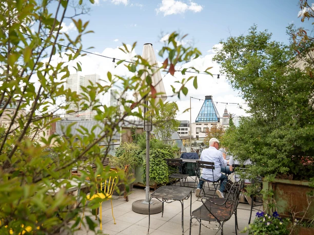 Begrünte Dachterrasse der Ruby Louise Bar mit Sitzplätzen und Blick auf Frankfurts Skyline