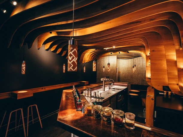 The interior of Woods Bar, featuring a curved wooden ceiling, a bar, and warm lighting