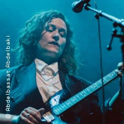 Billie Bird spielt Gitarre auf der Bühne im blauen Konzertlicht.