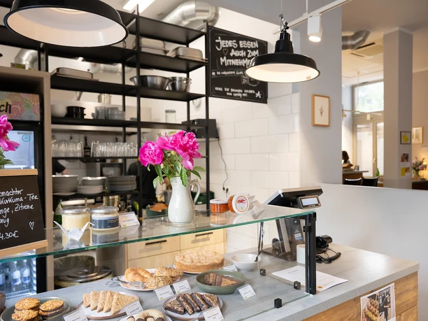 Frankfurt - Bio-Bistro Sachsenhausen Theke im Bio-Bistro Sachsenhausen mit Gebäck, Blumen, Tafel und offenen Regalen