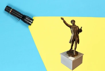 Im Schein einer Taschenlampe sieht man eine kleine Statue auf einem Sockel.