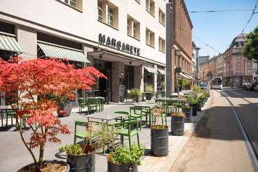 Sonniger Außenbereich des MARGARETE mit grünen Stühlen an der Braubachstraße in Frankfurt