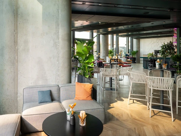 Oaks Bar mit hellen Loungeplätzen, Pflanzen und Panoramafenstern über Frankfurt
